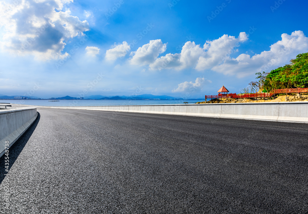 Asphalt road and beautiful seaside scenery under blue sky.