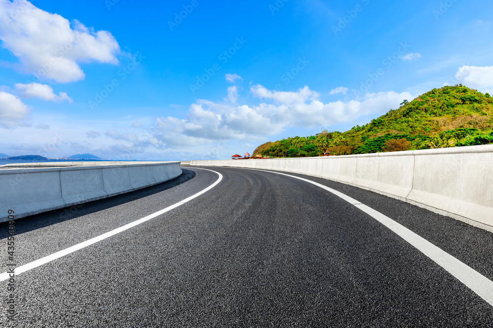 Asphalt road and beautiful seaside scenery under blue sky.