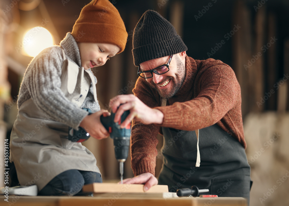 Father and son drilling wooden detail in workshop