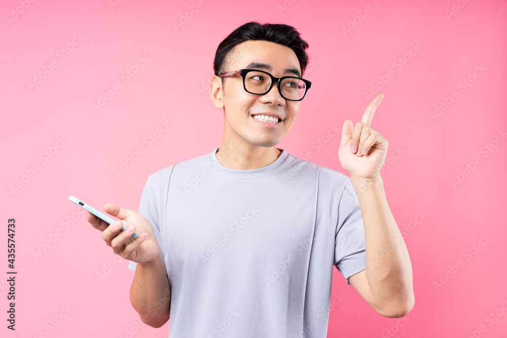 Portrait of Asian man using smartphone on pink background