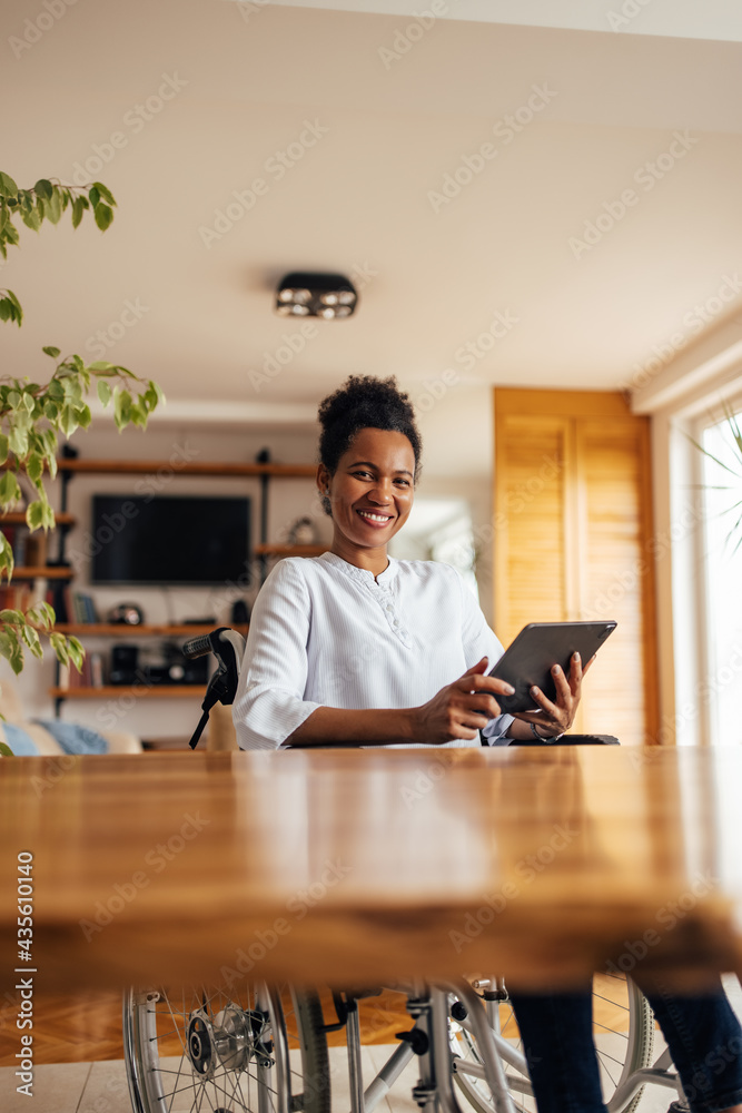 Happy woman in a wheelchair, using digital tablet.