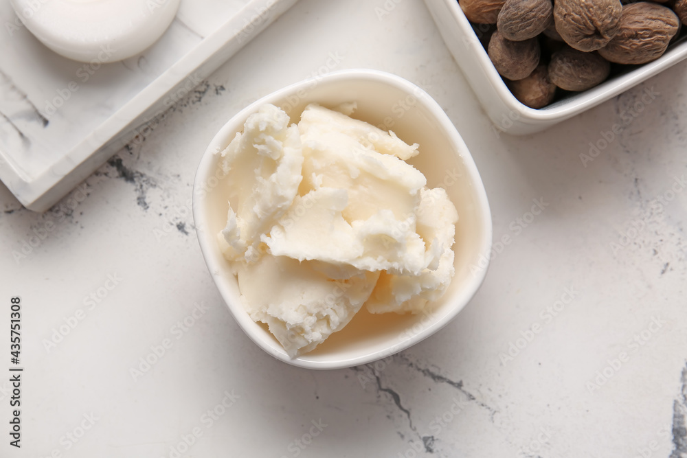 Bowl with shea butter on light background