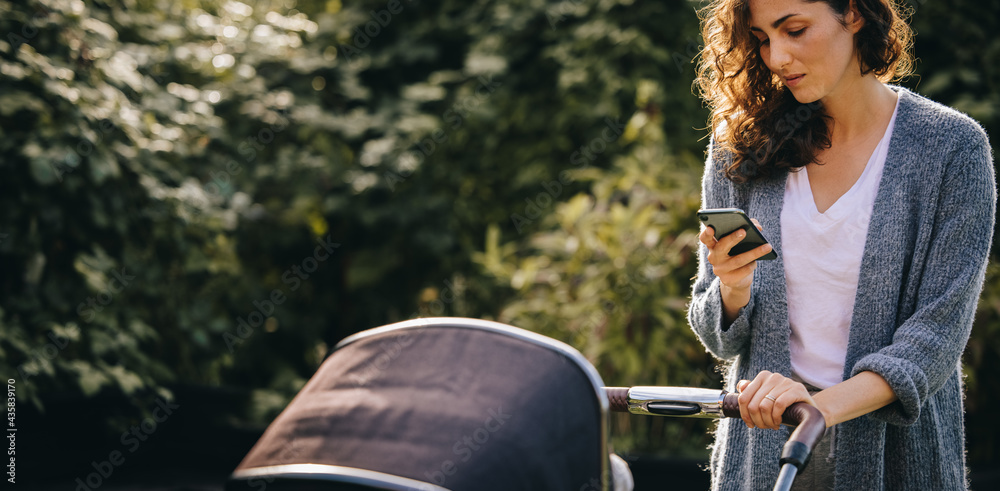 Mother pushing stroller and texting on phone