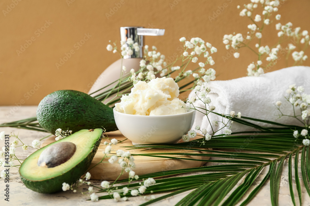 Composition with shea butter, avocado and floral decor on table