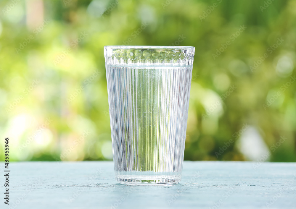 Glass of fresh cold water on table outdoors