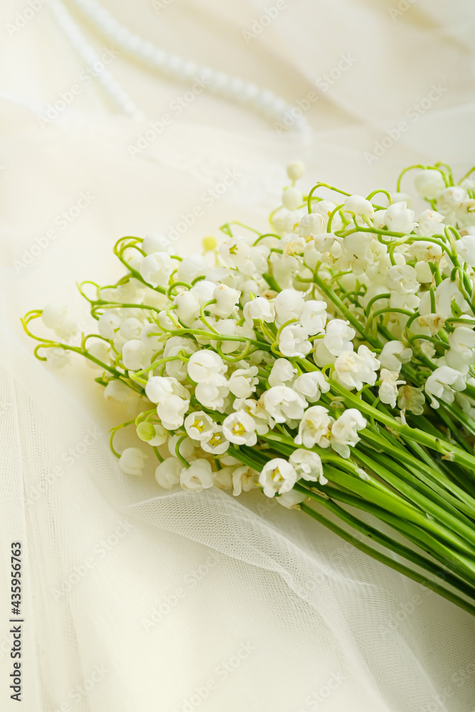 Beautiful lily-of-the-valley flowers on fabric background