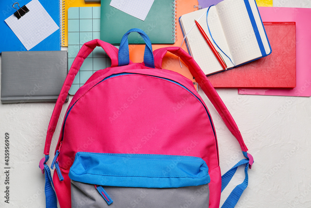 School backpack and stationery on light background