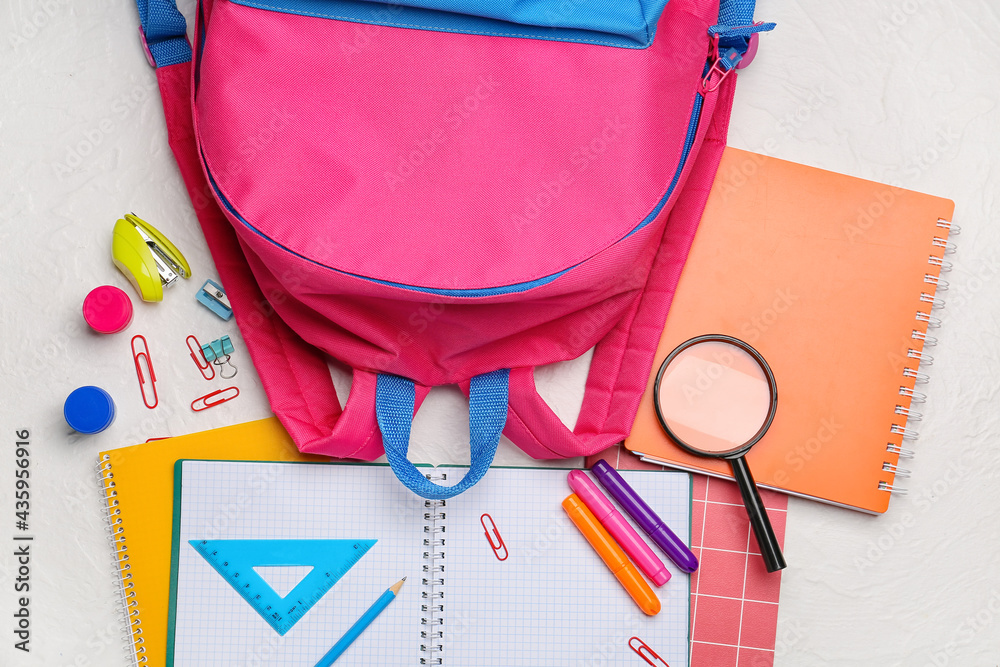 School backpack and stationery on light background