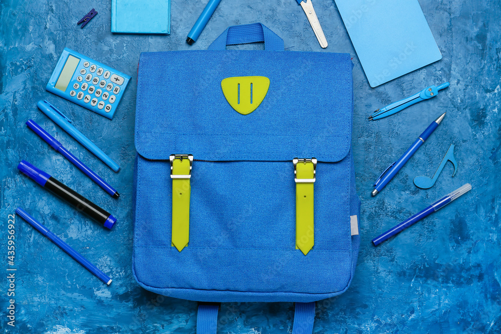 School backpack and stationery on color background