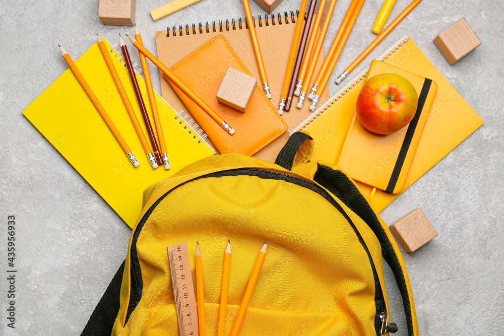 School backpack and stationery on light background