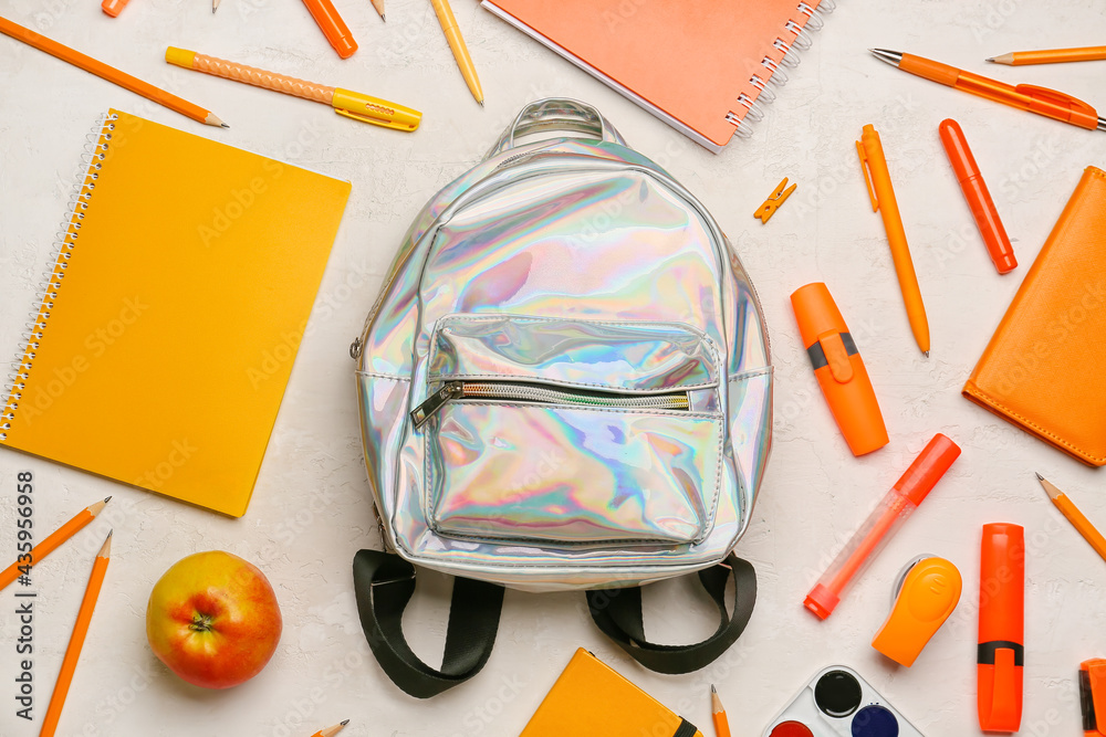 School backpack and stationery on light background