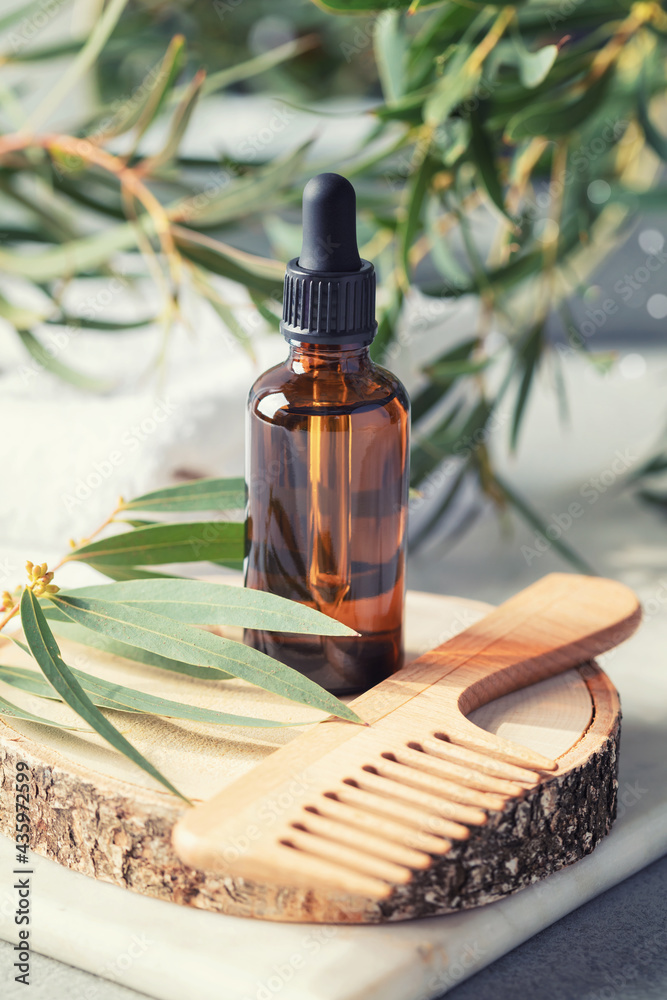 Amber glass transparent bottle with eucalyptus leaves and wooden hair brush