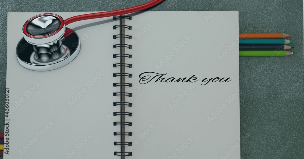 Composition of notebook with thank you note with coloured pencils and stethoscope on desk