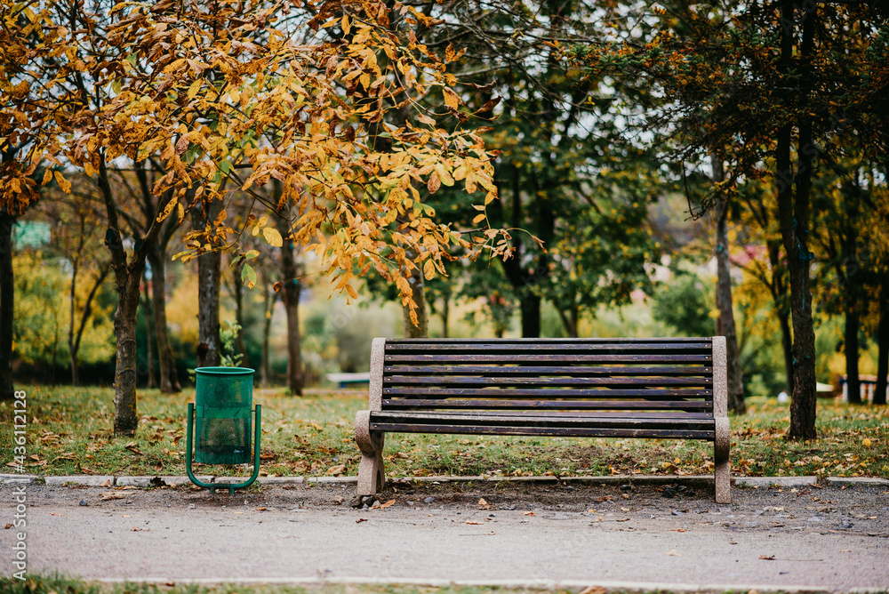 An urn next to an empty park bench.