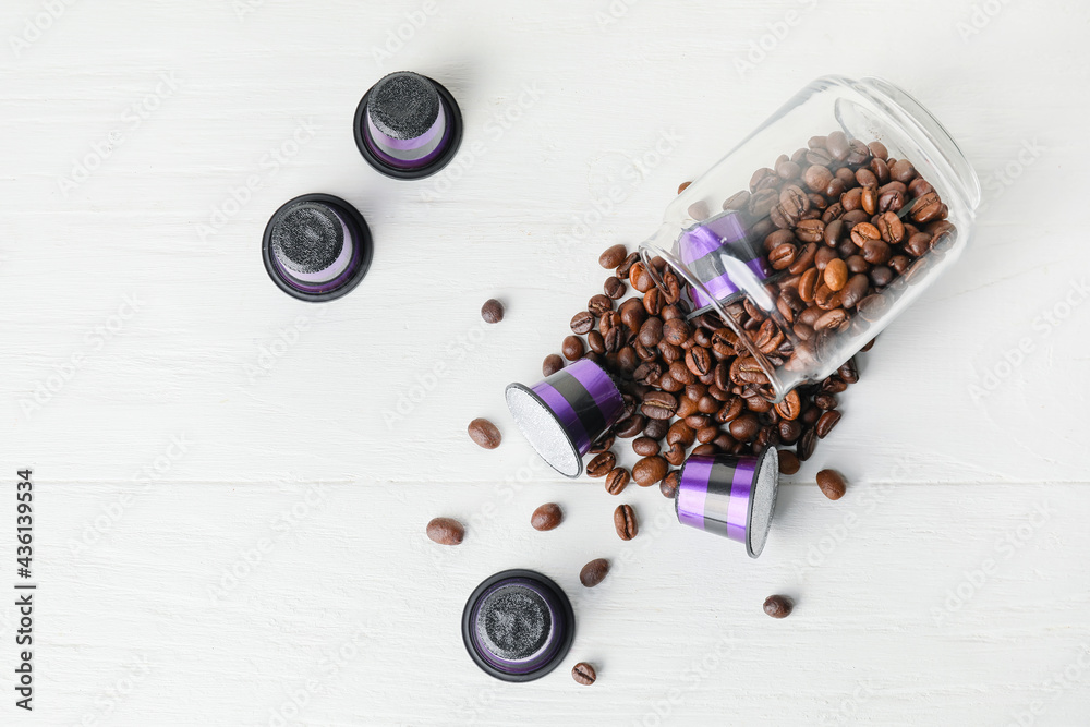 Jar with coffee beans and capsules on table