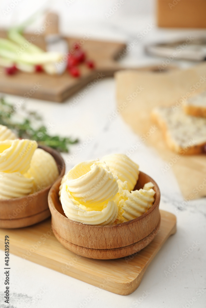 Wooden bowls with fresh butter on table