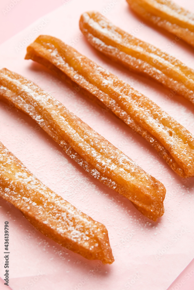 Parchment with tasty churros on color background, closeup