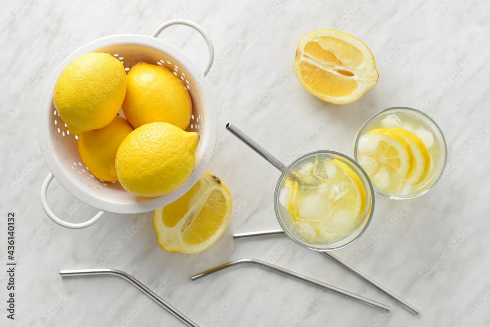 Composition with glasses of tasty cold lemonade and fruits on light background