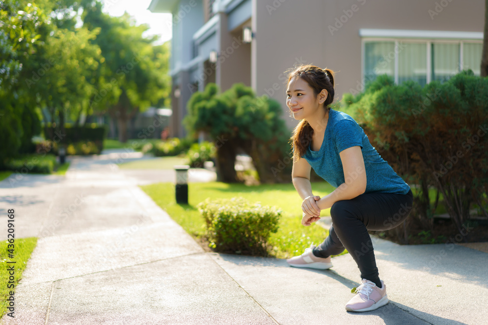 Asian woman stretching to warm up or cool down, before or after exercise, near the front door in the