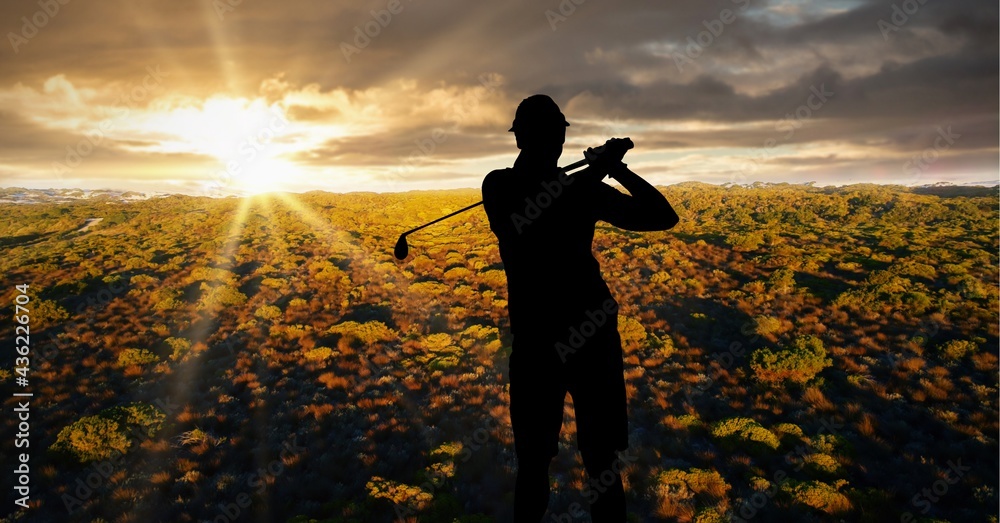 Composition of silhouette of male golf player over landscape and sunset