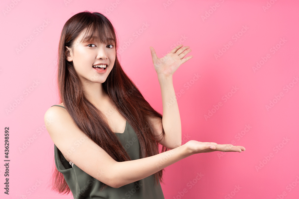 Portrait of a beautiful young asian girl posing on a pink background