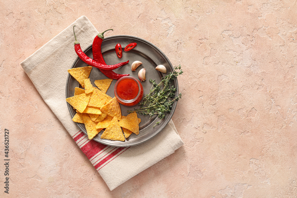 Tray with tasty chili sauce, nachos and ingredients on color background