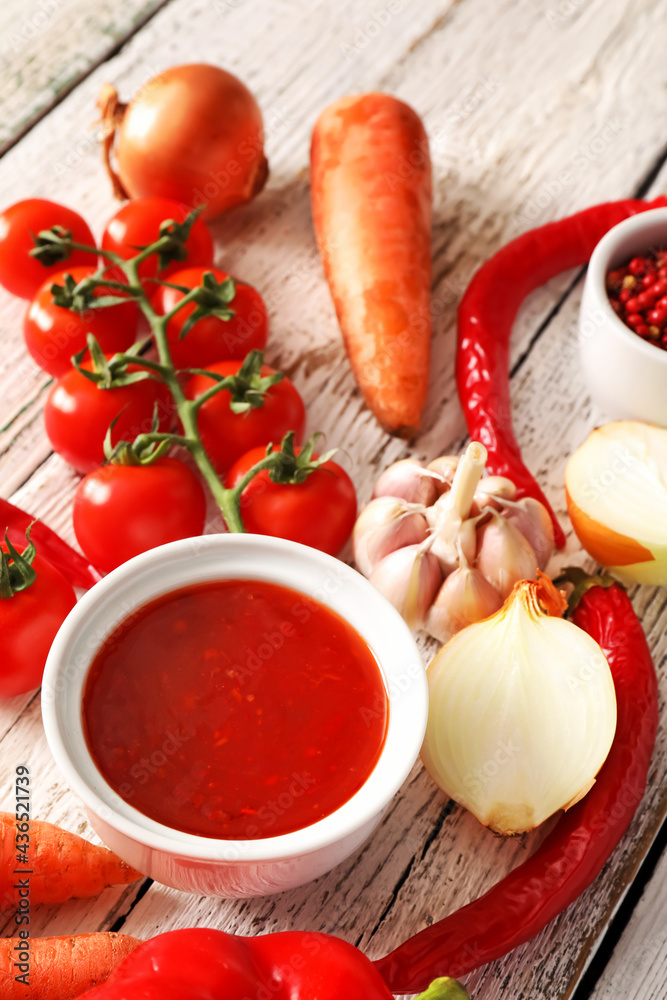 Composition with tasty chili sauce and ingredients on light wooden background