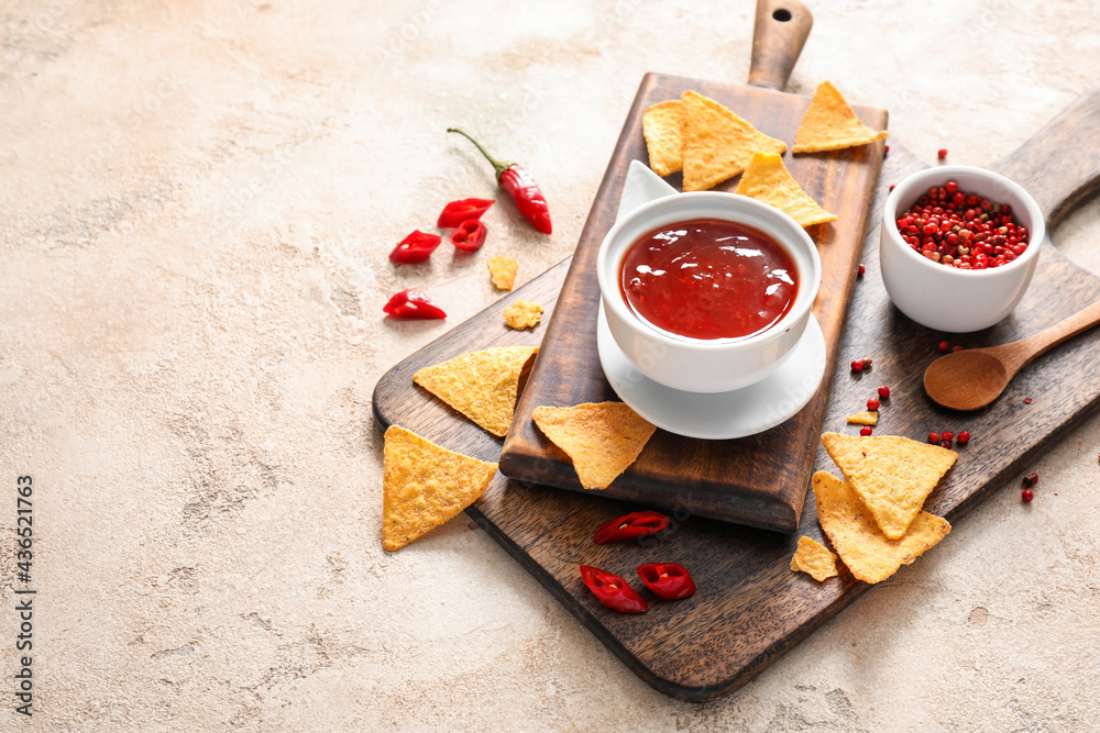 Composition with tasty chili sauce, nachos and peppercorns on light background