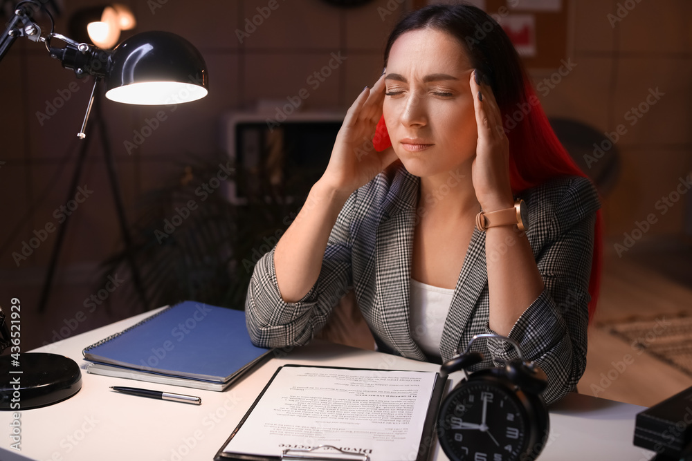 Tired beautiful woman working in office at night