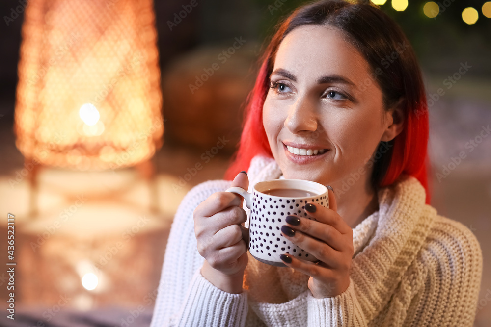 Beautiful woman drinking hot cocoa at home on Christmas eve, closeup