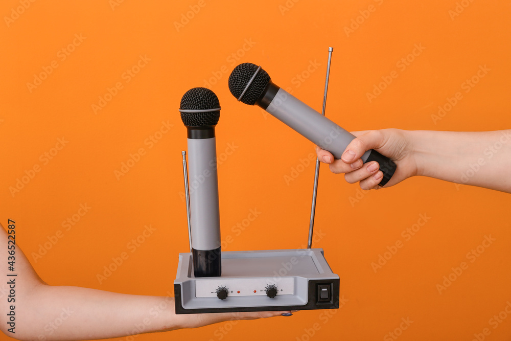 Female hands with modern microphones and audio system on color background