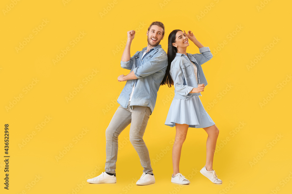 Happy young couple dancing on color background