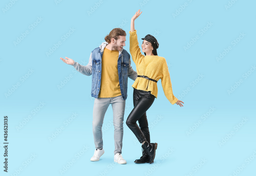 Happy young couple dancing on color background