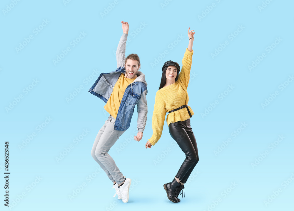 Happy young couple dancing on color background