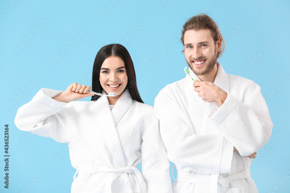 Young couple brushing teeth on color background