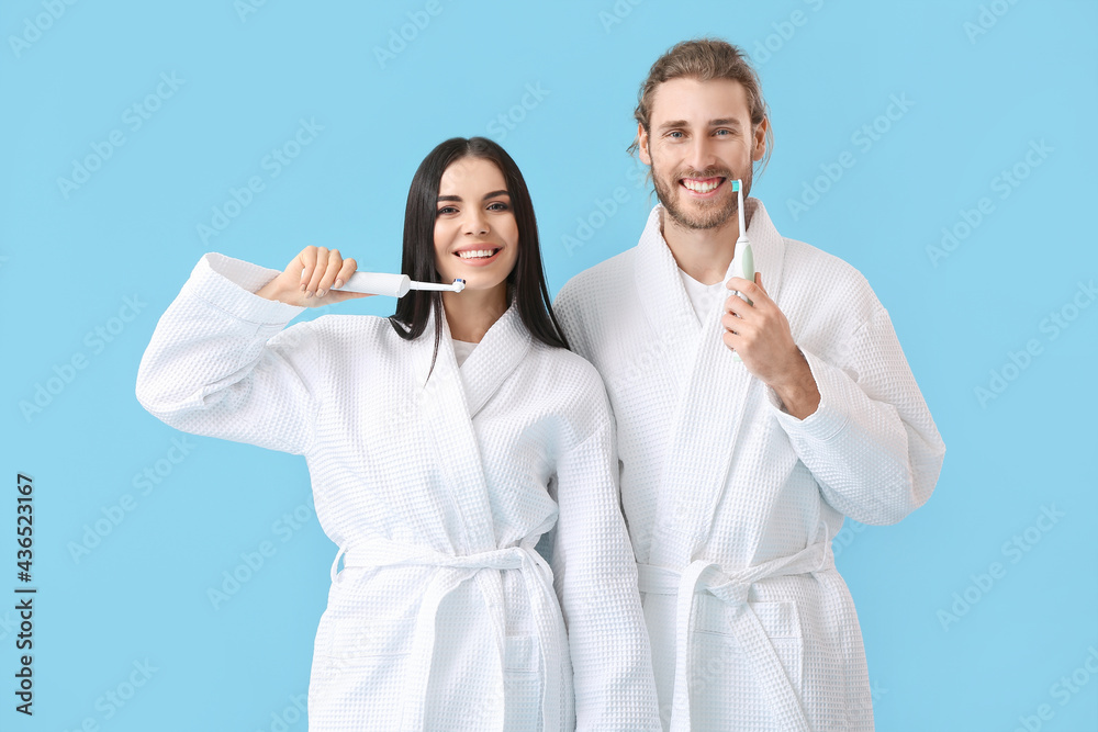 Young couple brushing teeth on color background