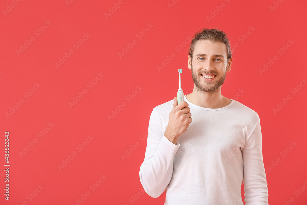 Handsome man with tooth brush on color background