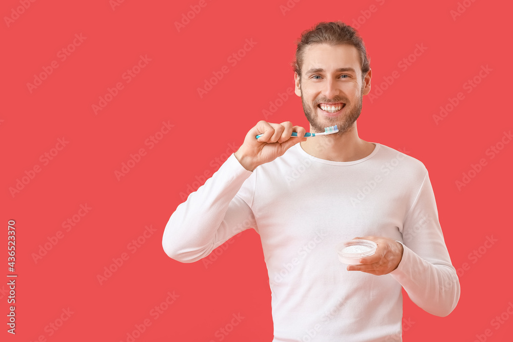 Handsome man brushing teeth on color background