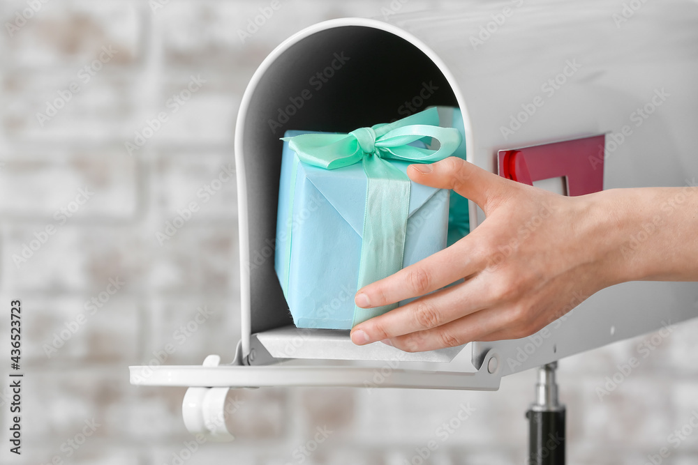 Woman getting gift from box on brick background