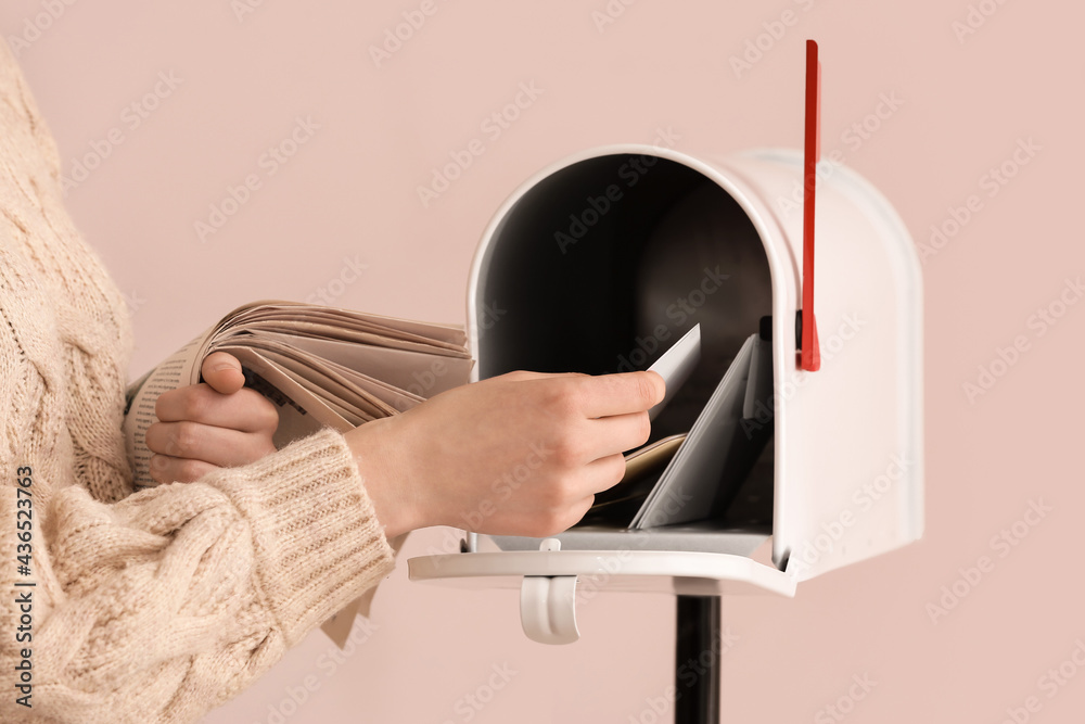 Woman getting letter from box on light background