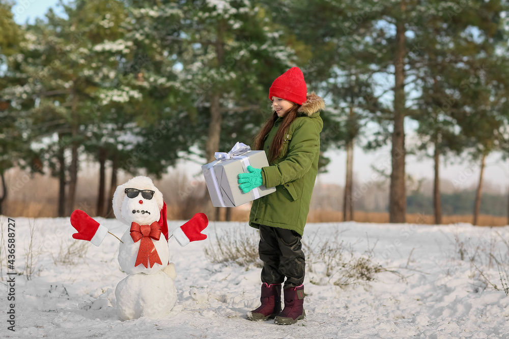 公园里带着礼盒和雪人的小女孩