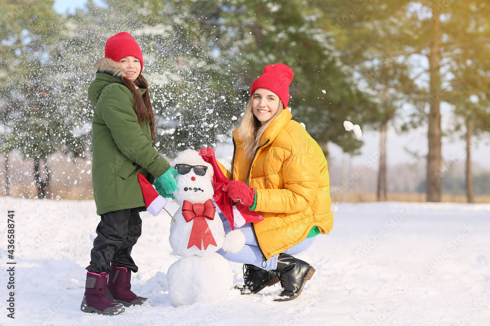 Happy family making snowman in park