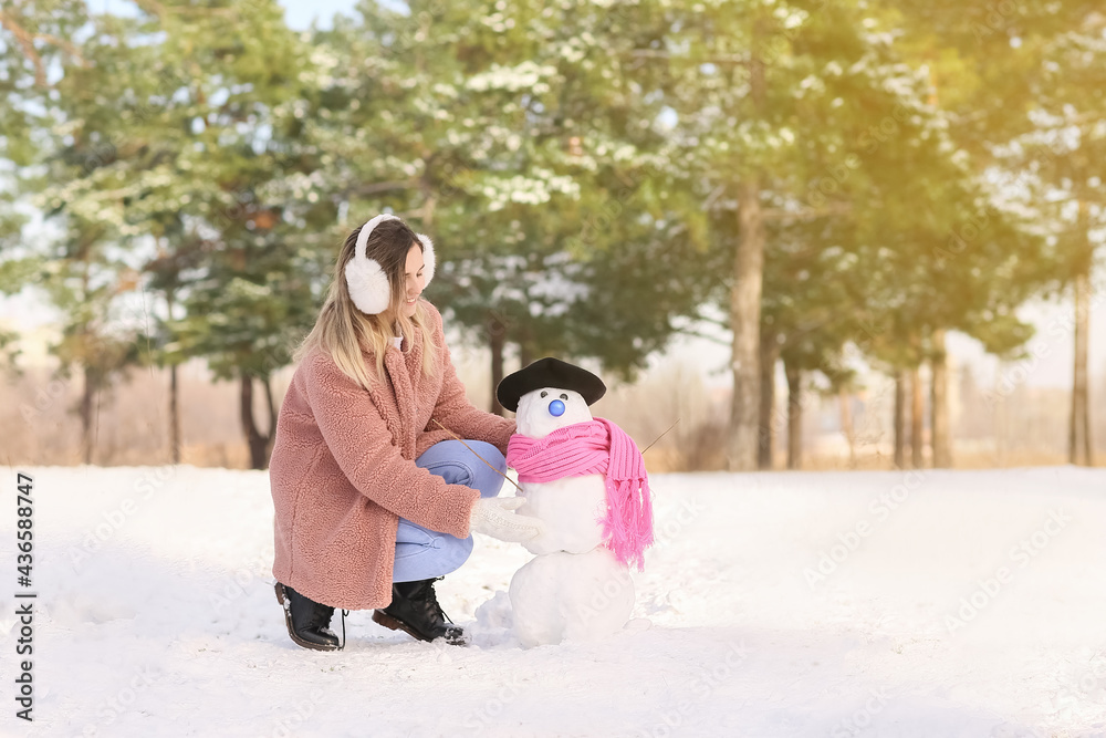 公园里有雪人的快乐年轻女人