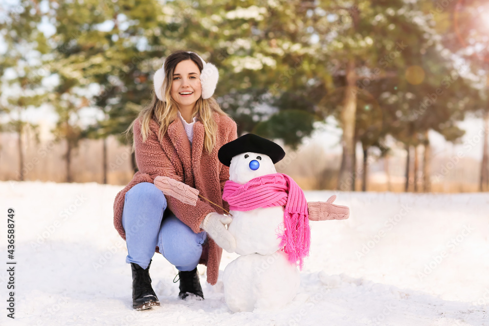 公园里有雪人的快乐年轻女人