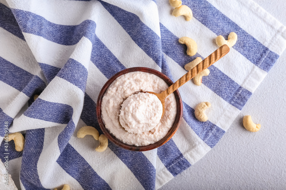 Bowl and spoon with cashew sour cream on table