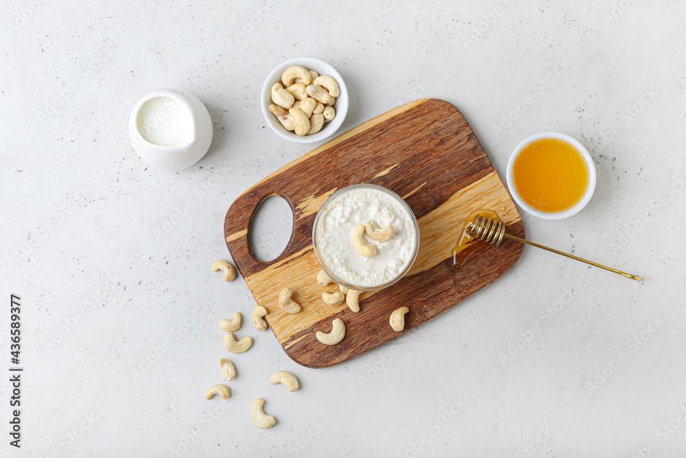 Composition with cashew sour cream, nuts and honey on light background