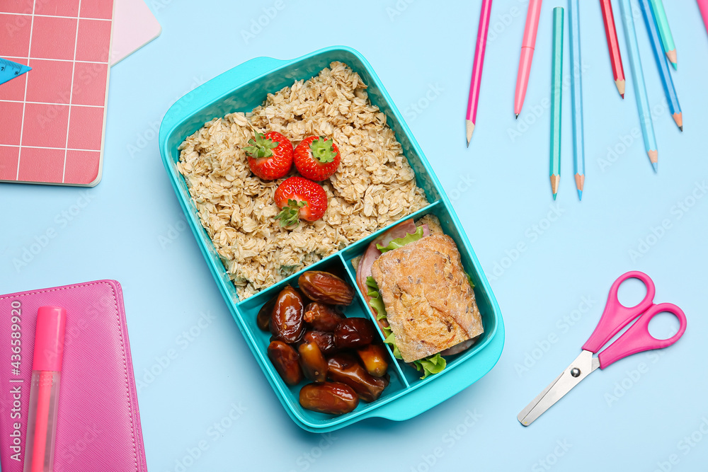 Lunchbox with tasty food and stationery on color background