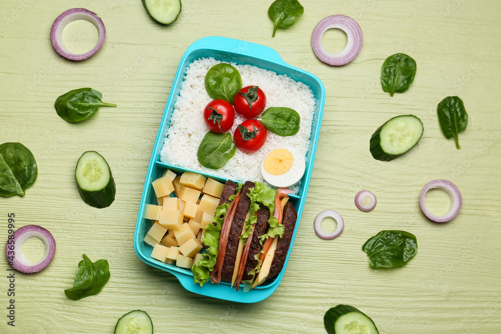 Lunchbox with tasty food on color wooden background