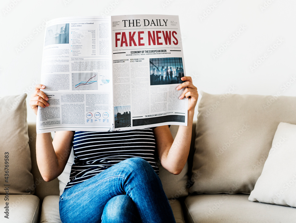 Woman reading newspaper with fake news