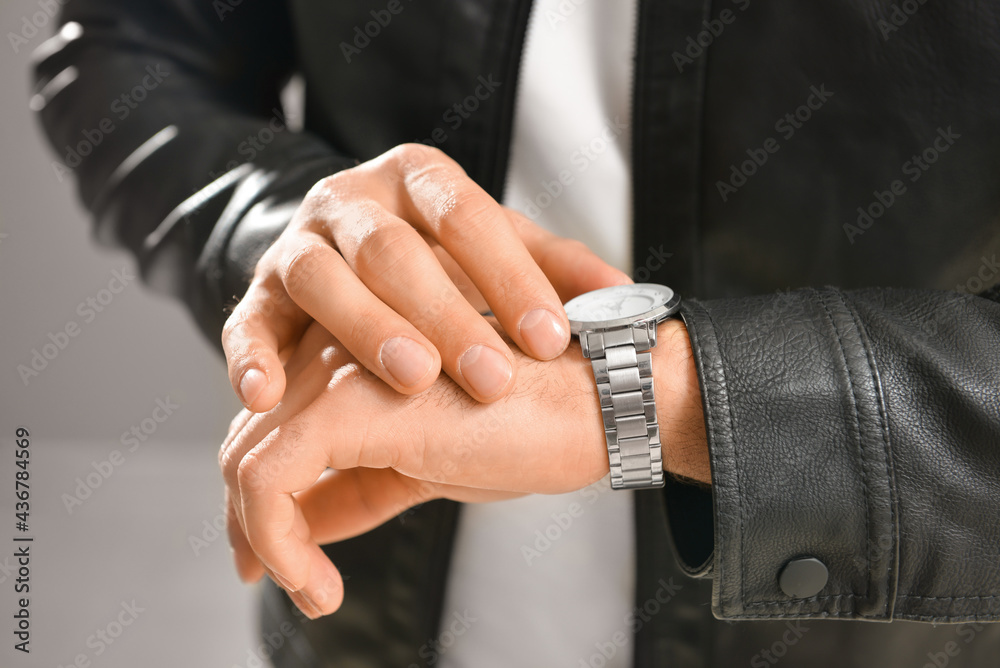 Fashionable young man with watch on grey background, closeup